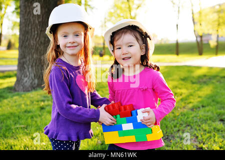 Süße kleine Mädchen in weißen Bau Helme spielen in Designer für Kinder im Park Stockfoto