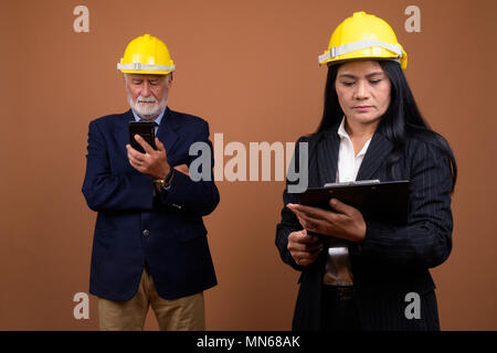 Ausgereifte multi-ethnischen Geschäft Paar gegen braunen Hintergrund Stockfoto