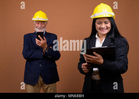 Ausgereifte multi-ethnischen Geschäft Paar gegen braunen Hintergrund Stockfoto