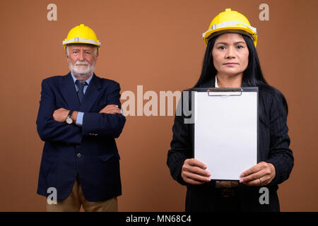 Ausgereifte multi-ethnischen Geschäft Paar gegen braunen Hintergrund Stockfoto