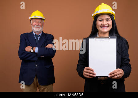 Ausgereifte multi-ethnischen Geschäft Paar gegen braunen Hintergrund Stockfoto