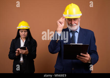Ausgereifte multi-ethnischen Geschäft Paar gegen braunen Hintergrund Stockfoto