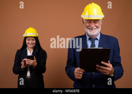 Ausgereifte multi-ethnischen Geschäft Paar gegen braunen Hintergrund Stockfoto