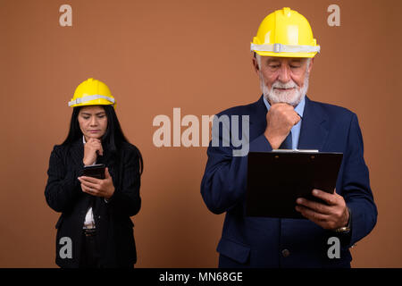 Ausgereifte multi-ethnischen Geschäft Paar gegen braunen Hintergrund Stockfoto