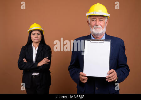 Ausgereifte multi-ethnischen Geschäft Paar gegen braunen Hintergrund Stockfoto