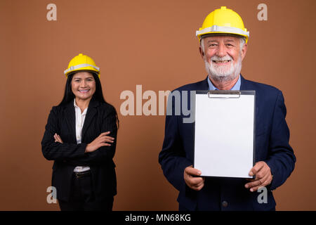 Ausgereifte multi-ethnischen Geschäft Paar gegen braunen Hintergrund Stockfoto