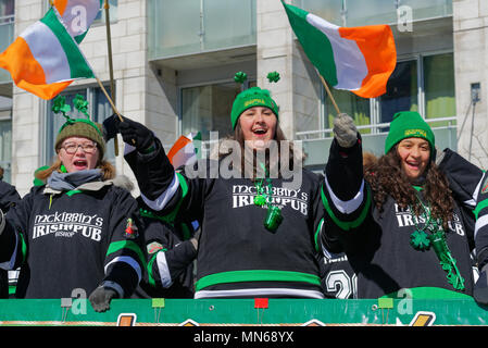 Mädchen auf dem McKibbins Irish Pub float Winken irische Flaggen in der Montreal St. Patricks Day Parade Stockfoto