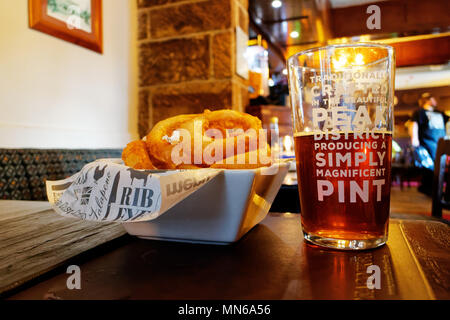 Ein Pint Bier und den Zwiebelringen auf einen Tisch. Der Pub ist der Pfau Hotel in Bakewell und das Bier ist vor Ort gebraut. Stockfoto