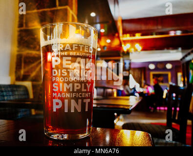 Sonnenstrahl scheint durch ein Pint Bier auf einen Tisch. Der Pub ist der Pfau Hotel in Bakewell und das Bier ist vor Ort gebraut. Stockfoto