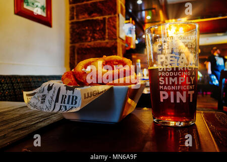 Sonnenstrahl scheint durch ein Pint Bier auf einen Tisch. Der Pub ist der Pfau Hotel in Bakewell und das Bier ist vor Ort gebraut. Stockfoto