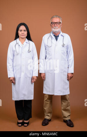 Ausgereifte multi-ethnischen paar Ärzte gegen braunen Hintergrund Stockfoto
