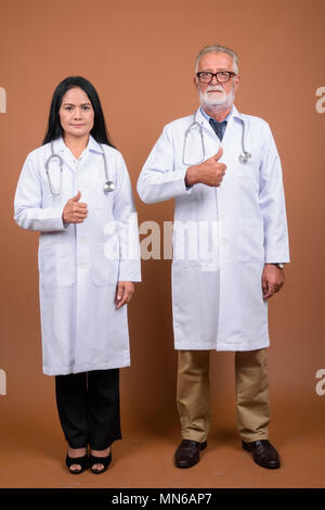Ausgereifte multi-ethnischen paar Ärzte gegen braunen Hintergrund Stockfoto