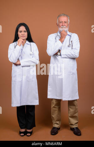 Ausgereifte multi-ethnischen paar Ärzte gegen braunen Hintergrund Stockfoto