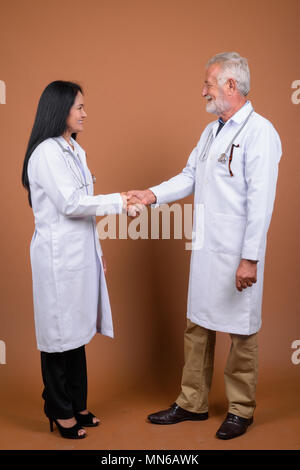 Ausgereifte multi-ethnischen paar Ärzte gegen braunen Hintergrund Stockfoto