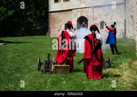 Soldaten, die in den traditionellen, rote Uniformen Aufnahmen aus alten Kanonen und Gewehren auf Fest'Tage der Medjimurje County" | Cakovec Stockfoto