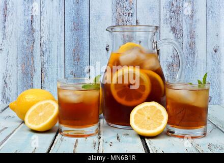 Krug Eistee mit zwei Gläsern und Zitronen auf rustikalen blau Holz Hintergrund Stockfoto