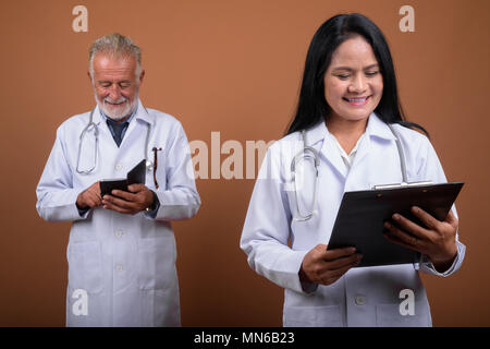 Ausgereifte multi-ethnischen paar Ärzte gegen braunen Hintergrund Stockfoto