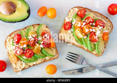 Avocado Toasts mit Hummus und Tomaten, Ansicht von oben auf weißem Hintergrund Stockfoto