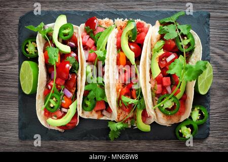 Würziger Fisch Tacos mit Wassermelone salsa und Avocados, Ansicht von oben auf schiefer Server Stockfoto