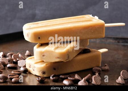 Gestapelte Kaffee und Chocolate Chip Eis am Stiel gegen einen rustikalen dunklen Hintergrund Stockfoto