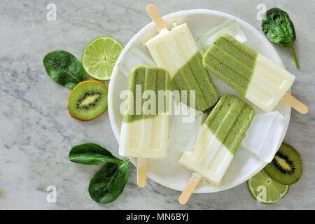 Gesunden grünen Smoothie Eis am Stiel mit Kiwi, Kalk und Spinat auf eine weiße Marmorplatte, Ansicht von oben Stockfoto
