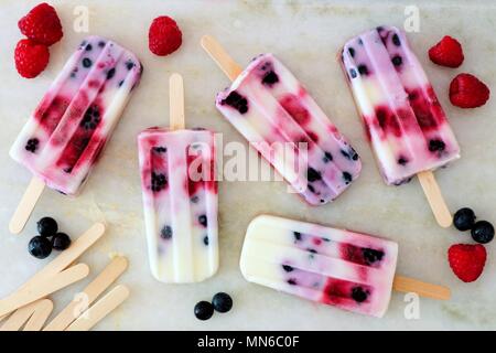 Gesunde gemischte Beeren Joghurt Eis am Stiel mit Obst auf einem weißen Marmor Hintergrund Stockfoto