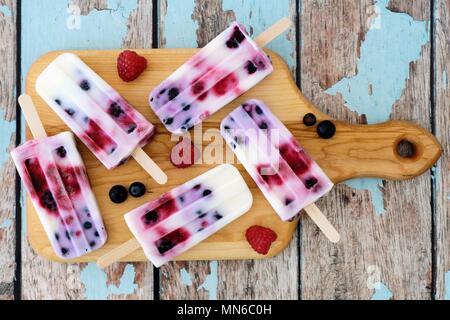 Hausgemachte mixed berry Joghurt Eis am Stiel auf einem Paddle Board mit rustikalen Hintergrund Stockfoto
