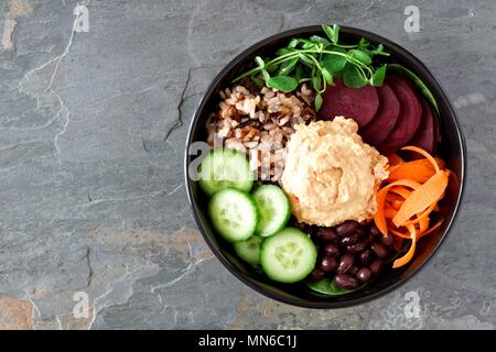 Gesunde vegetarische Salat Schüssel mit Hummus, Bohnen, wilder Reis, rote Rüben, Karotten, Gurken und Erbse Eintragfäden. Oben Blick auf schiefer Hintergrund. Stockfoto