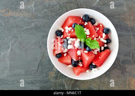 Sommer Salat mit Wassermelone und Feta, Blaubeeren, oben Blick auf einem dunklen Stein Hintergrund Stockfoto