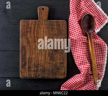 Leeren alten hölzernen Schneidebrett und einem Löffel aus Holz auf einem schwarzen Tabelle, Ansicht von oben Stockfoto