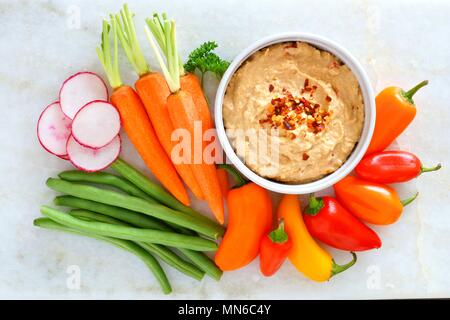 Hummus Dip mit einer Vielzahl von frischem Gemüse, oben Blick auf einen weißen Hintergrund Stockfoto