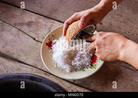 Frau mit Hand kratzen Coconut stellen Sie den Behälter für den Nachtisch machen und Essen. Stockfoto