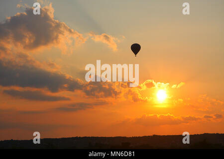 Ein Ballon fliegen über den Himmel, während die Sonne hinter dem golden Wolken geht. Stockfoto
