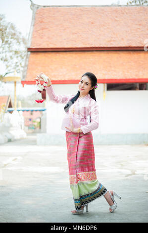 Porträt der schönen thailändischen Frau in Thai Tracht tanzen vor dem Tempel und weiß Girlande halten. Sie lächelt und sieht an Kamera Stockfoto