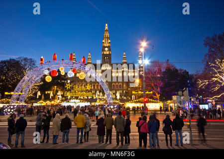 Blick über den Rathausplatz in Wien in der Weihnachtszeit. Menschen besuchen den Christkindlmarkt und deshalb warten an der Ampel die Straße überqueren Stockfoto