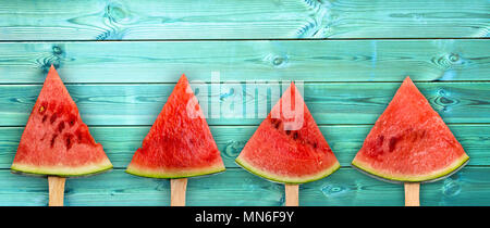 Vier Wassermelone Schicht Eis am Stiel auf Panoramablick auf die blaue Holz Hintergrund, frische Sommer Obst Konzept Stockfoto