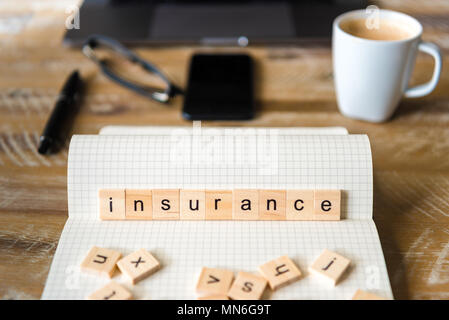 Nahaufnahme auf das Notebook um Holz Tisch Hintergrund, auf Holzblöcken mit Buchstaben, Versicherung Wort konzentrieren. Business Concept Bild. Stockfoto