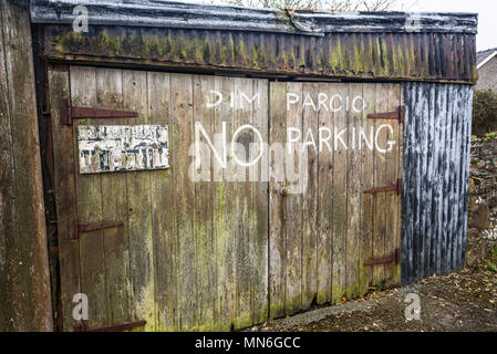 Von Hand bemalt kein Parkplatz schild in Englisch und Walisisch auf einer alten Garage Schuppen. Stockfoto