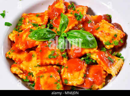 Frische ravioli Pasta mit Petersilie und Basilikum Blätter, italienische Küche. Weiße Platte und Holztisch, Pasta. Stockfoto