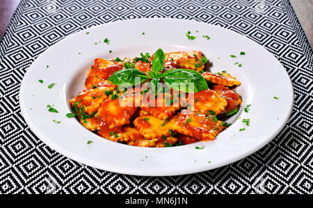 Frische ravioli Pasta mit Petersilie und Basilikum Blätter, italienische Küche. Weiße Platte und Holztisch, Pasta. Stockfoto