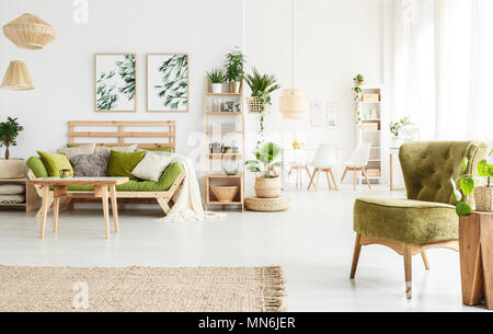 Helle geräumige Wohnung Innenraum mit Holz- , retro Sessel, Poster und einen Tisch mit Stühlen Stockfoto