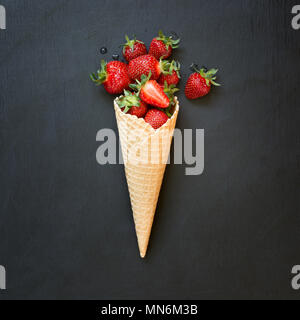 Frische organische Erdbeere im Eis auf Schwarz. Stockfoto