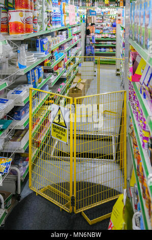 Eine gelbe Barriere mit einem Schild, auf dem "Mind the Gap) verhindert, dass Kunden fallen ein offenes Loch in ein Lebensmittelgeschäft. Stockfoto