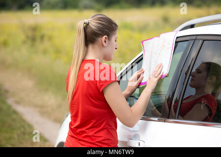 Junge Frau lehnte sich auf dem Auto und Roadmap Stockfoto