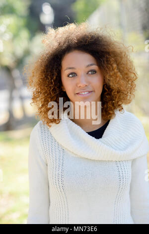 Schöne junge afrikanische amerikanische Frau mit Afro Frisur und grüne Augen tragen weiße Winter Dress Stockfoto