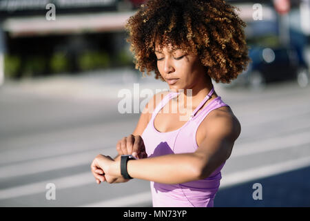 Junge schwarze Frau mit smartwatch berühren Touchscreen im Active Sports Activity. Mädchen mit afro Haar ihr smart Watch. Stockfoto