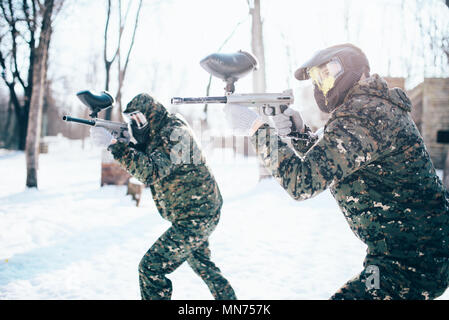 Paintball Team in Uniform Angriff im Winter Kampf. Extreme Sport Spiel, Soldaten in Schutz Masken und Tarnung hält mit der Waffe in der Hand Stockfoto