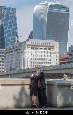 Zwei Liebende oder ein paar Kuscheln neben der Themse im Zentrum von London mit der Stadt London Financial. Bezirk im Hintergrund. Walkie Talkie. Stockfoto