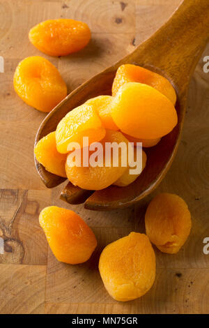 Ganze getrocknete Aprikosen Obst auf holzlöffel auf Holzbrett Hintergrund Stockfoto