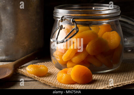 Ganze getrocknete Aprikosen Obst in Storage jar auf dunklen Holztisch Hintergrund Stockfoto